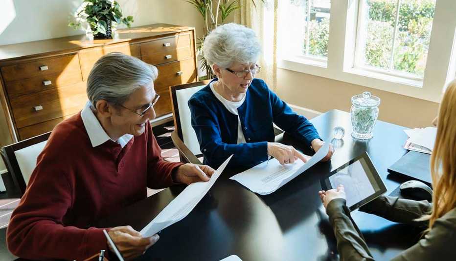 Pareja de adultos mayores con una asesora financiera en su oficina.