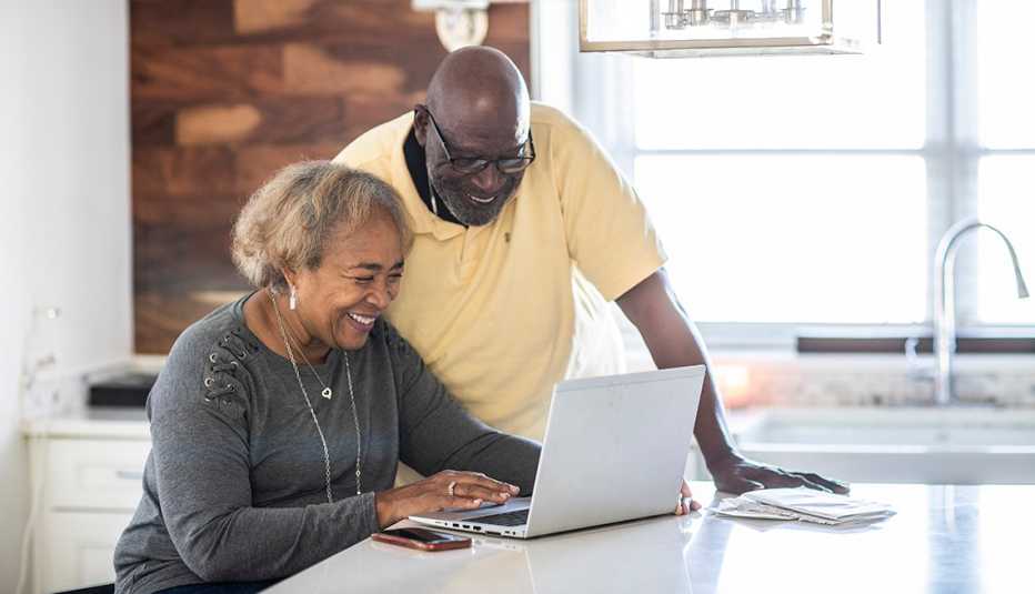Una pareja mayor usar la computadora portátil en su cocina.