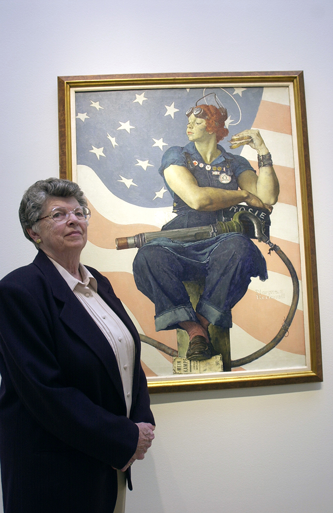 Mary Keefe, de 78 años, está parada junto a un póster de la película Rosie the Riveter de 1944 