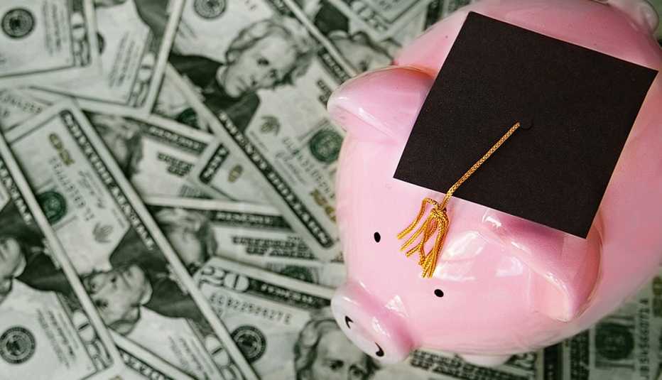 Alcancía sobre billetes de dólar con un birrete de graduación encima