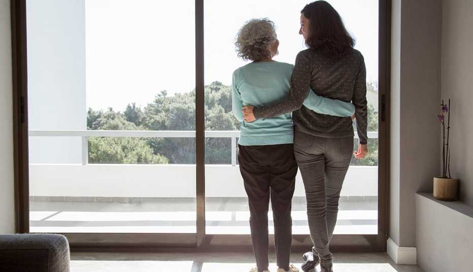 Dos mujeres abrazándose mientras miran por la ventana Dos mujeres abrazándose mientras miran por la ventana
