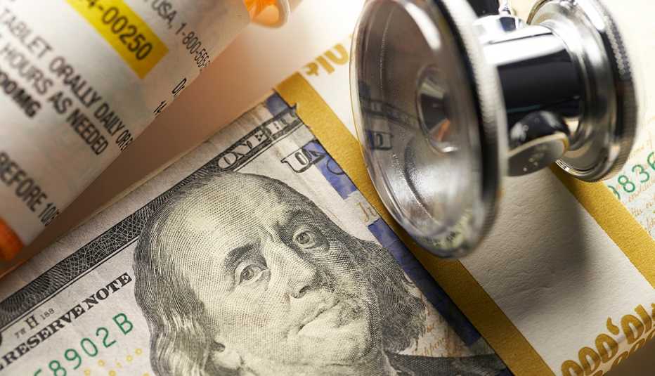 Frasco de medicamentos junto a un estetoscopio y un fajo de billetes