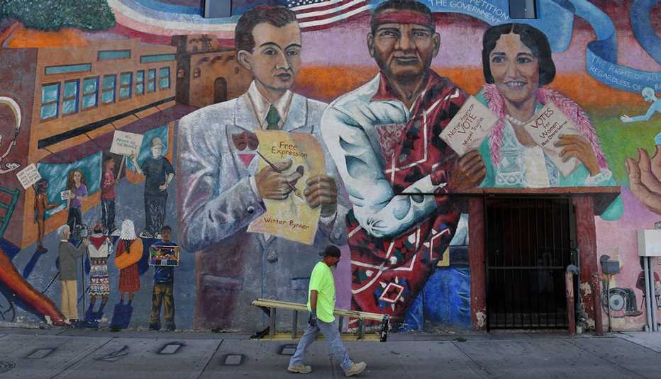 Un hombre pasa caminando junto a un mural en la pared de un edificio