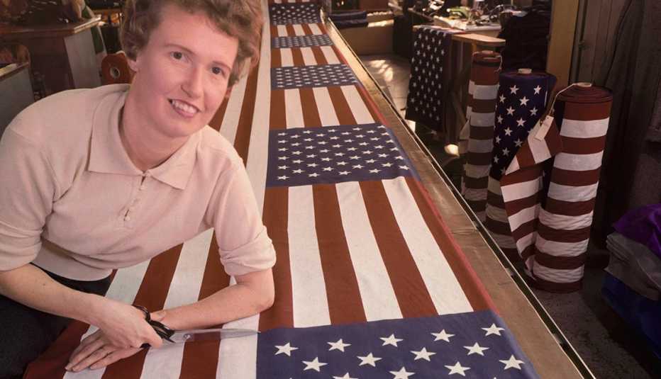 Mujer trabajadora de una fábrica inspeccionando una bandera americana