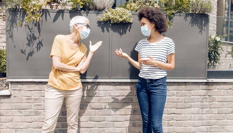 Dos mujeres que usan mascarillas sostienen una conversación 