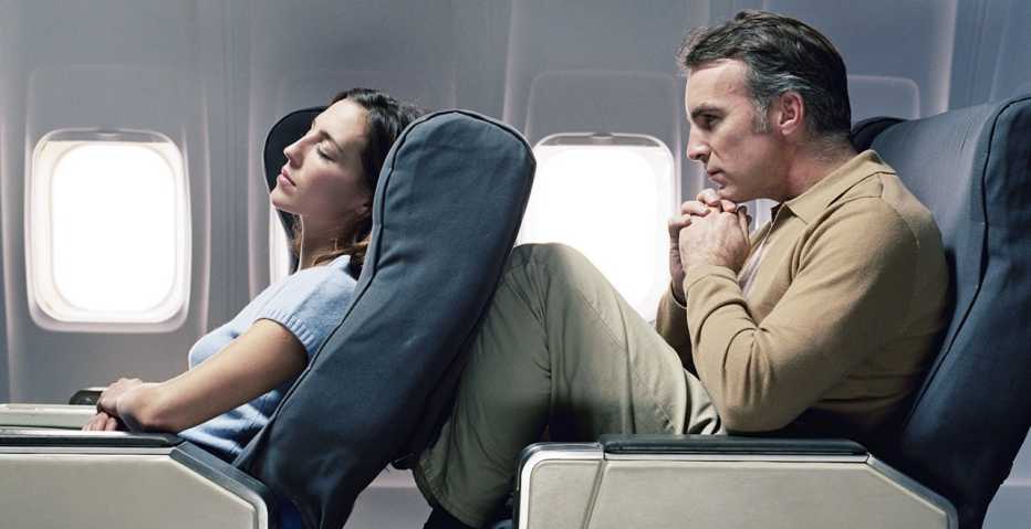 woman reclining airplane seat into a man's legs
