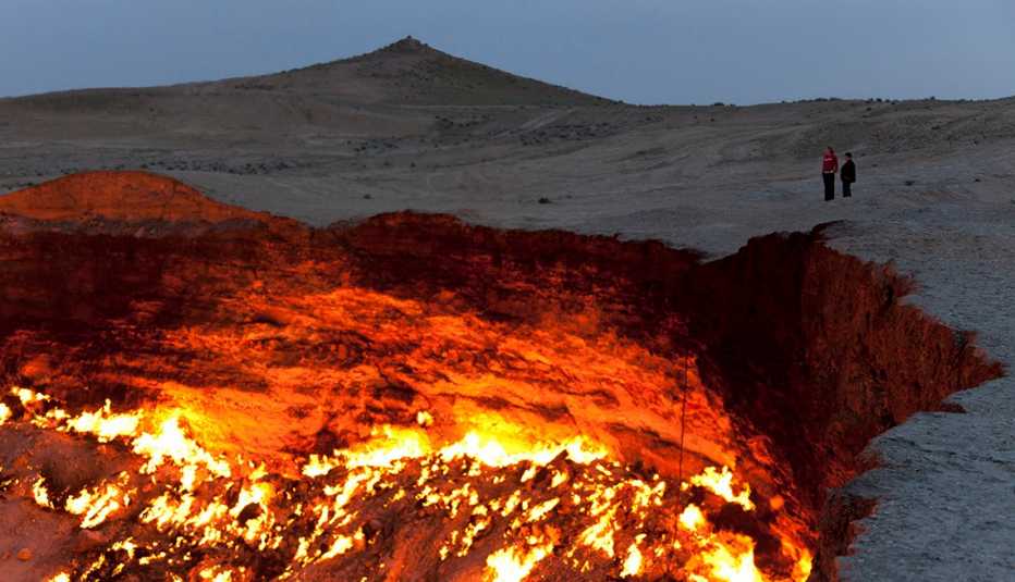 Couple Stand Overlooking The Crater In Karakum Desert In Derweze, Turkmenistan, Strange Overseas Destinations Couple Stand Overlooking The Crater In Karakum Desert In Derweze, Turkmenistan, Strange Overseas Destinations