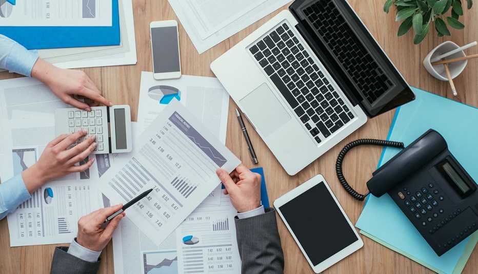 Escritorio lleno de documentos financieros y aparatos digitales