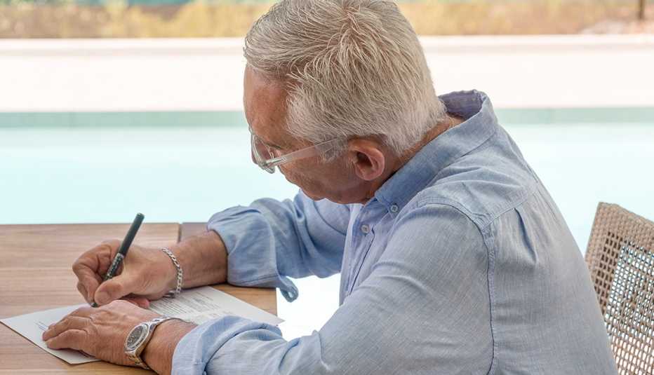 Un hombre escribe una nota sentado en un escritorio Un hombre escribe una nota sentado en un escritorio