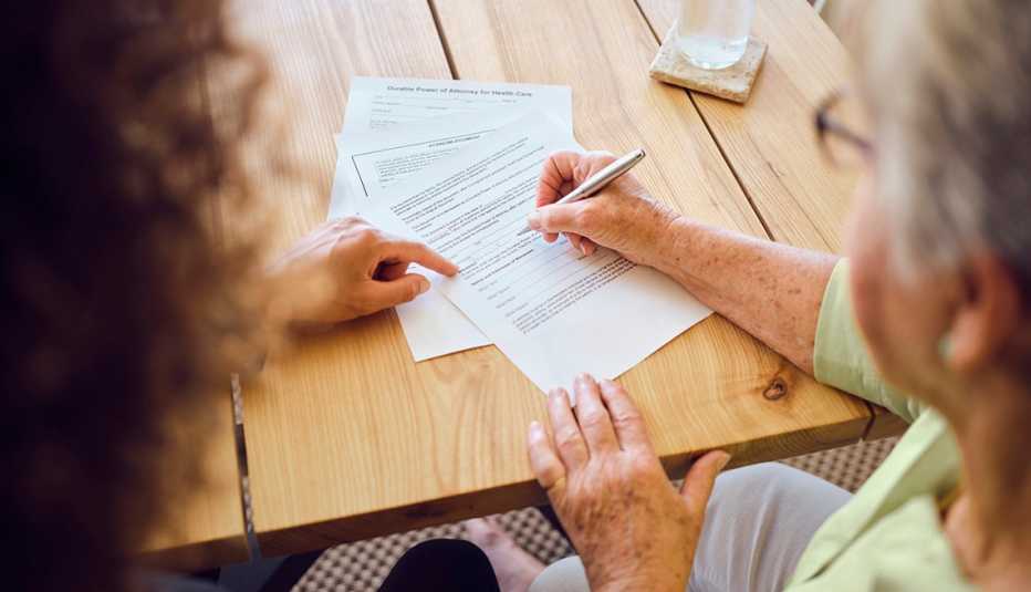 Una mujer mayor firma documentos legales.