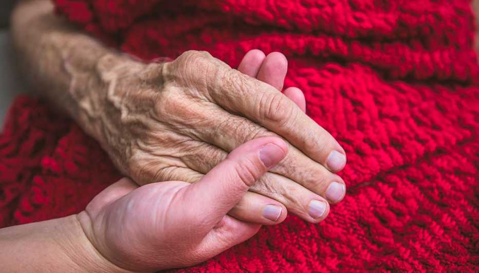 Persona joven sostiene la mano de un anciano