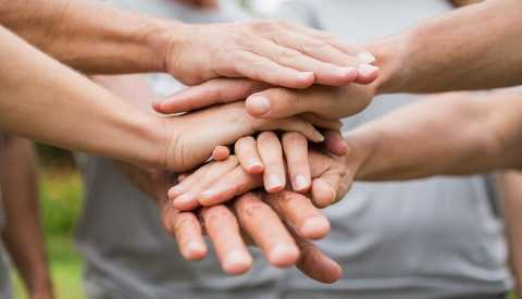 Manos sobre manos en apoyo de grupo.