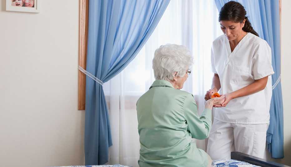 Enfermera dándole un medicamento a una mujer mayor