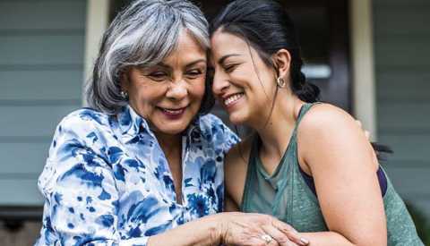 Una mujer mayor es abrazada por su hija.