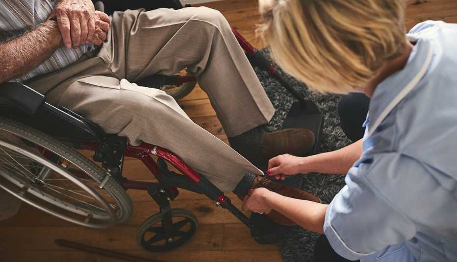 Mujer amarra los zapatos de un hombre en silla de ruedas Mujer amarra los zapatos de un hombre en silla de ruedas