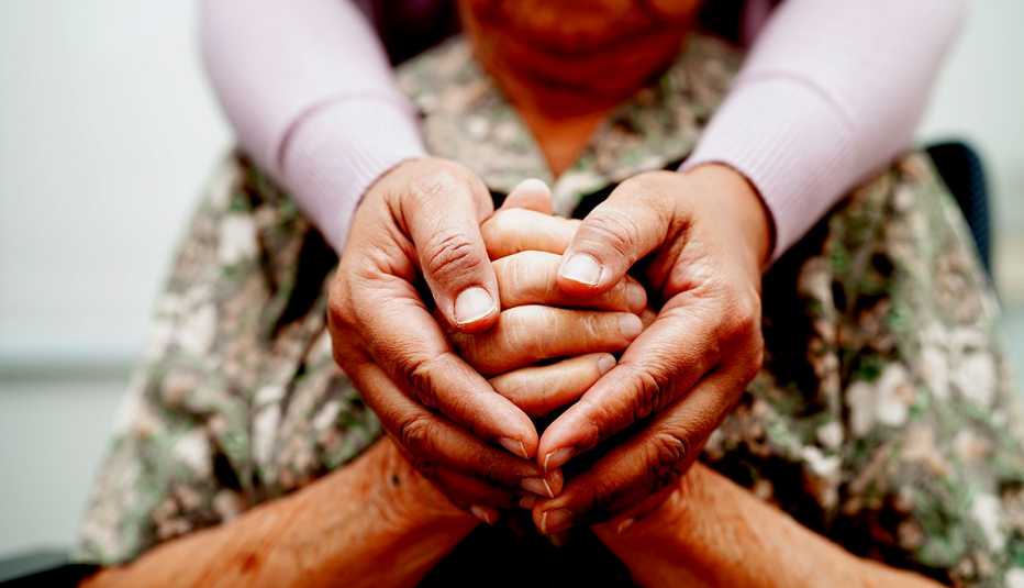 Un cuidador toma de la mano a una anciana.