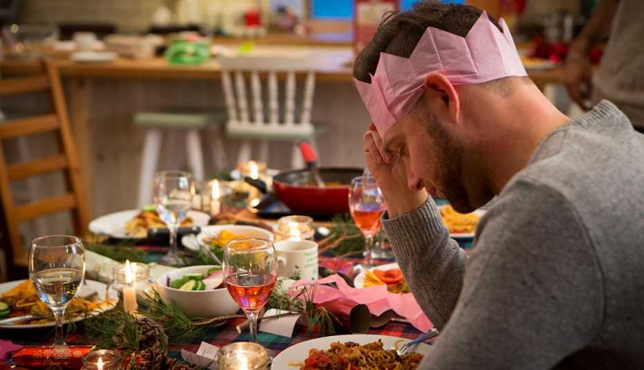 Hombre sentado en una mesa decorada para las fiestas luciendo solo y triste. Hombre sentado en una mesa decorada para las fiestas luciendo solo y triste.