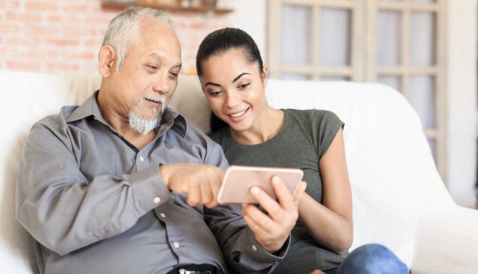 Hija adulta ayuda a su papá a usar un teléfono celular