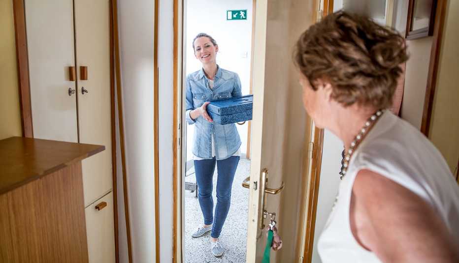 Una mujer entregando comida a una cuidadora.