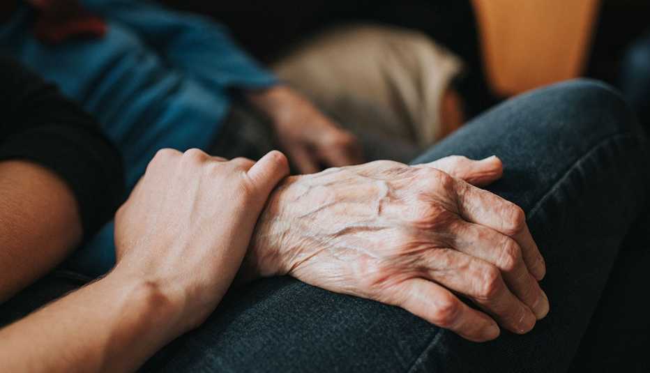 Una persona más joven tiene la mano sobre la mano de una persona mayor. Una persona más joven tiene la mano sobre la mano de una persona mayor.