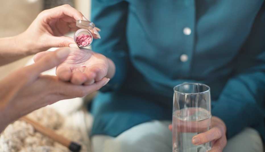 Una enfermera dando medicamento a una mujer mayor.
