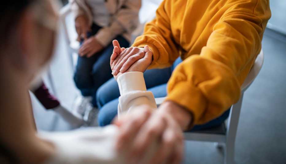 Personas en un grupo de apoyo tomados de la mano.