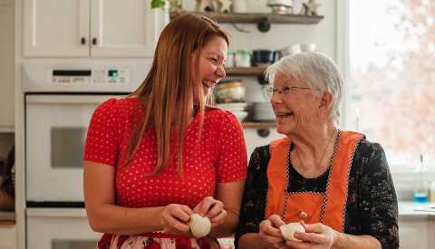 Una mujer mayor y su hija juntas en la cocina.