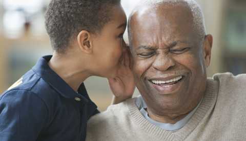 Un nieto afroamericano le susurra a su abuelo en el oíido