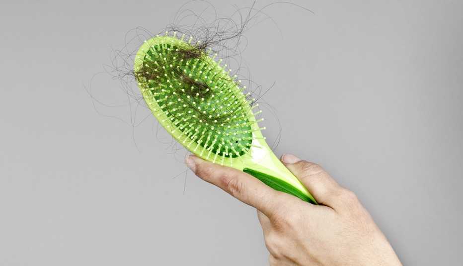 Cabello enredado en cepillo de pelo de color verde.