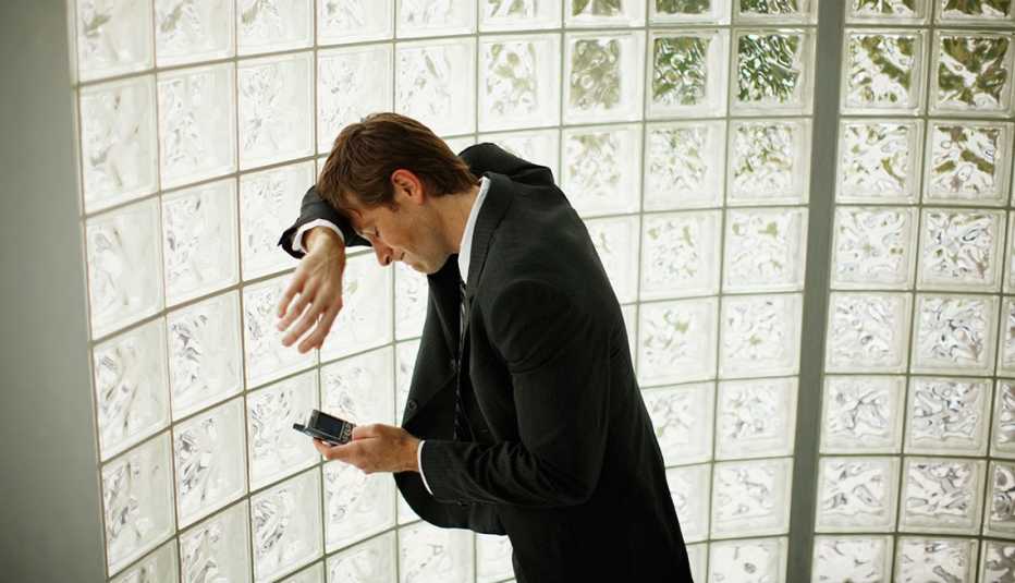Hombre recostado de una pared utilizando su teléfono inteligente Hombre recostado de una pared utilizando su teléfono inteligente