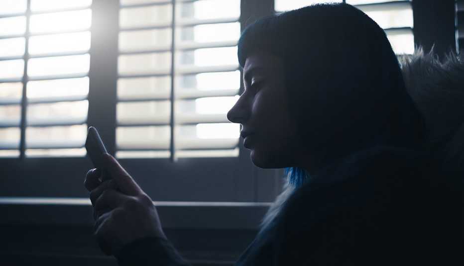 Mujer en penumbras mirando su celular Mujer en penumbras mirando su celular