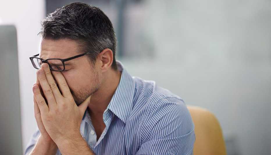 Hombre con sus manos en la cara en señal de agotamiento Hombre con sus manos en la cara en señal de agotamiento