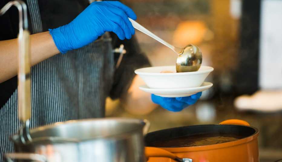 Una persona sirve sopa en un plato blanco