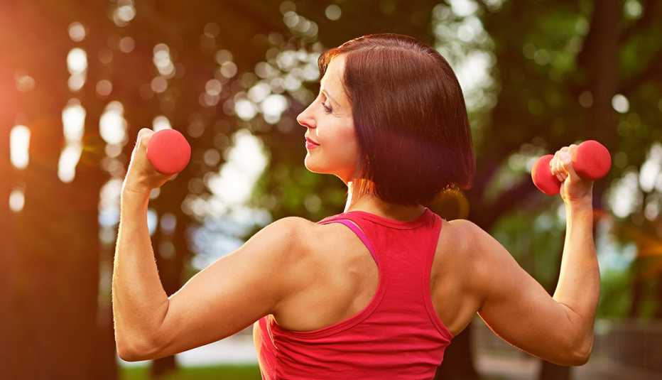 Mujer utilizando unas mancuernas al aire libre Mujer utilizando unas mancuernas al aire libre