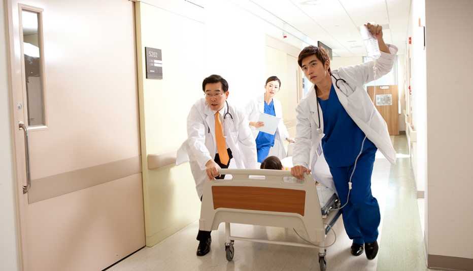 Tres médicos llevando a un paciente en camilla Tres médicos llevando a un paciente en camilla