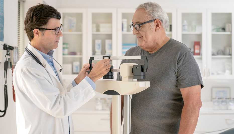 Médico pesando a su paciente Médico pesando a su paciente