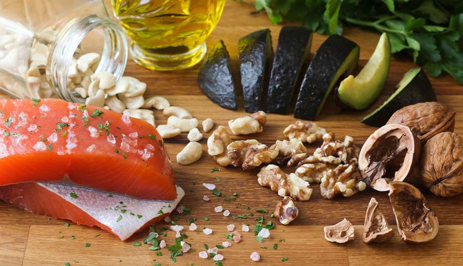 Pescado, ajos, aceite, aguacates y nueces sobre una mesa