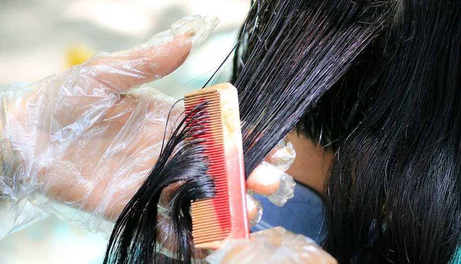 Estilista le pinta el cabello a una clienta Estilista le pinta el cabello a una clienta