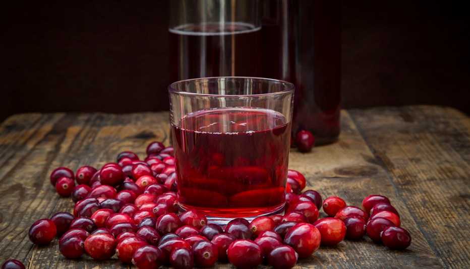 Un vaso con jugo de arándanos y arándanos frescos sobre una mesa