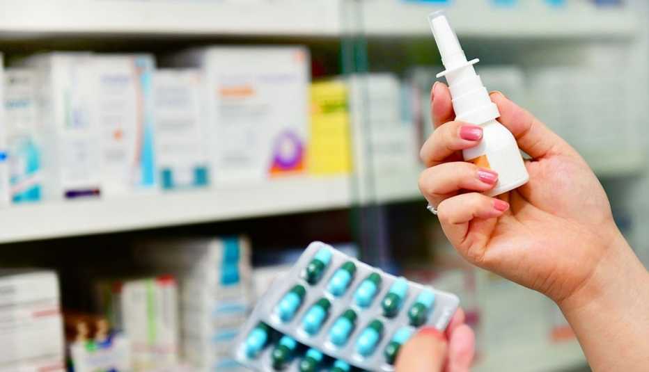 Mujer sostiene un aerosol nasal y varias pastillas