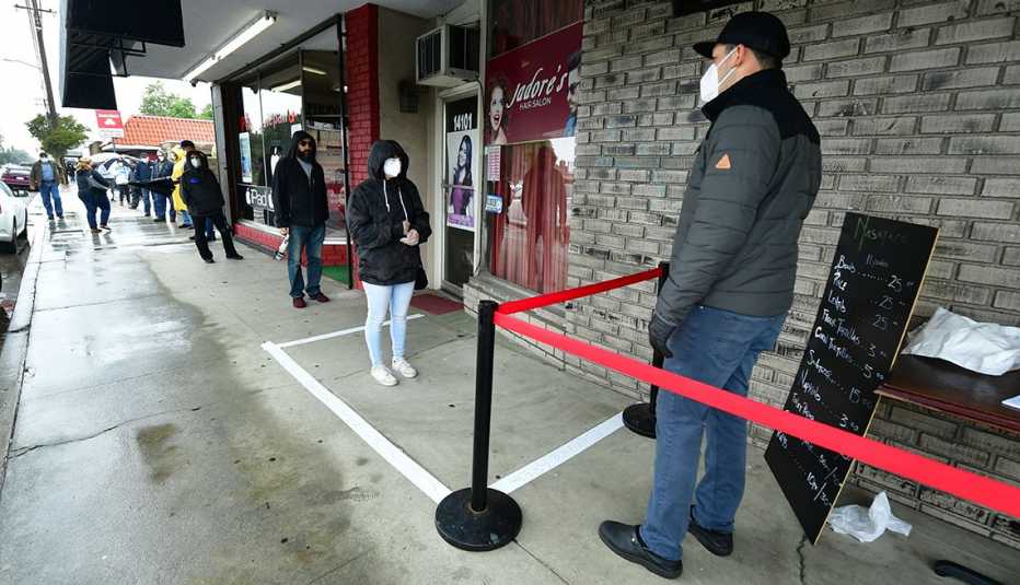 Personas hacen una fila guardando distancia