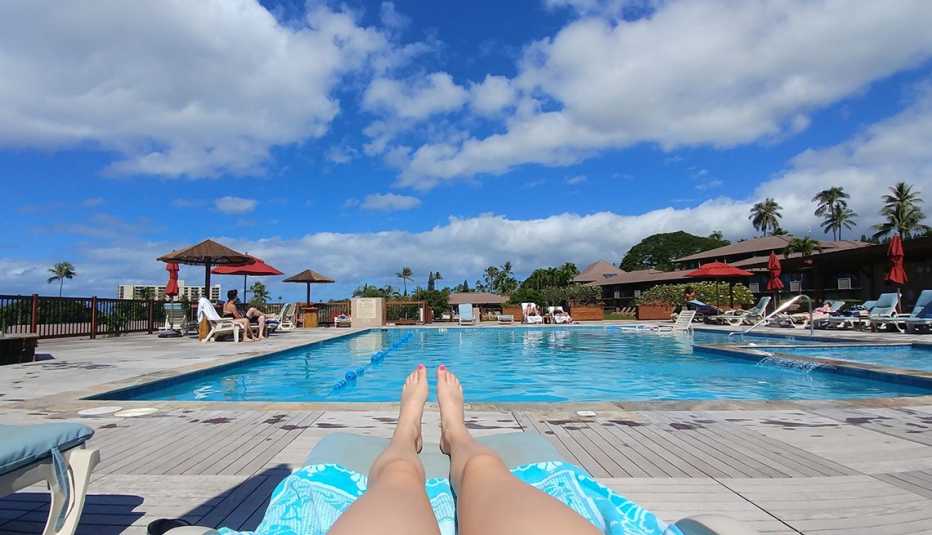 Piernas de una mujer mientras toma el sol cerca de una piscina
