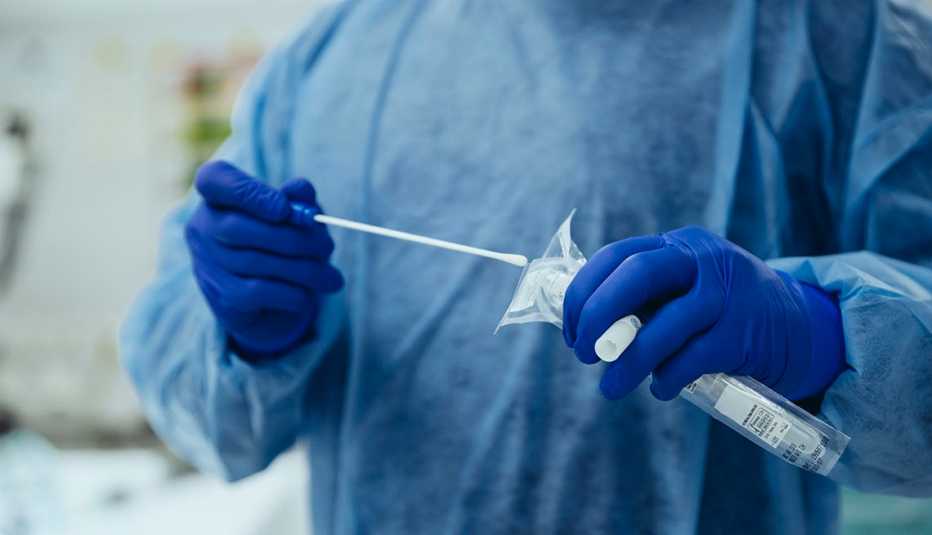 Técnico médico sostiene un tubo de ensayo y un hisopo para una prueba de covid-19