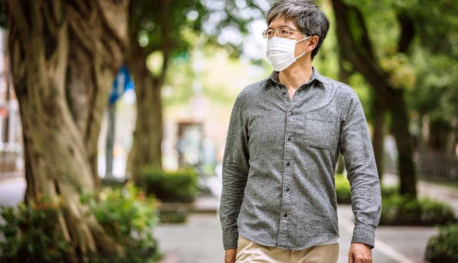 Un hombre camina por una acera usando una mascarilla