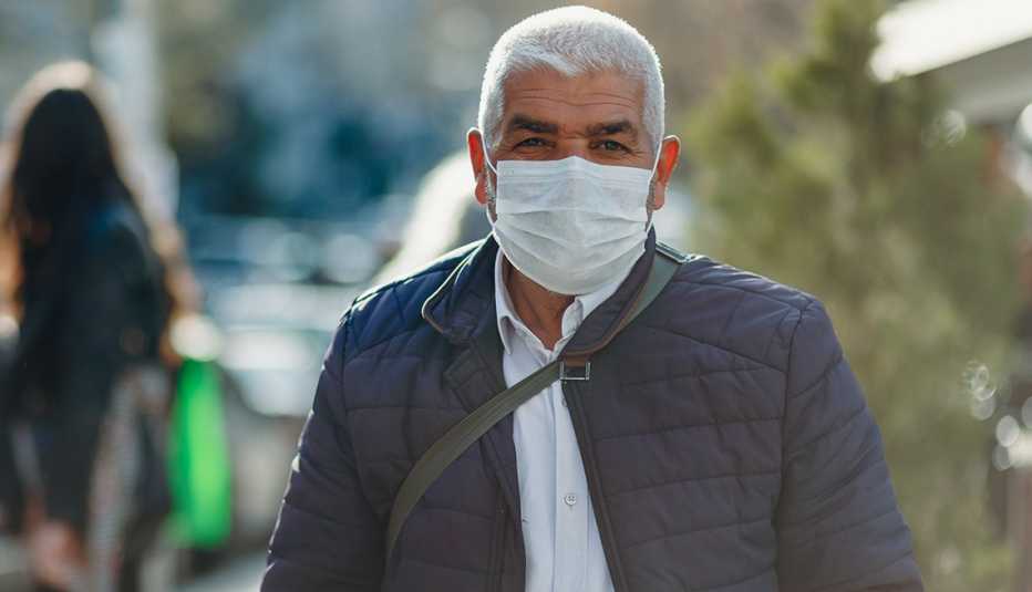 Un hombre usa una mascarilla mientras camina al aire libre Un hombre usa una mascarilla mientras camina al aire libre