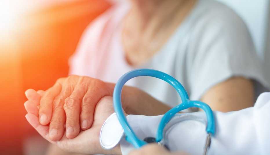 Persona mayor sostiene la mano de su médico