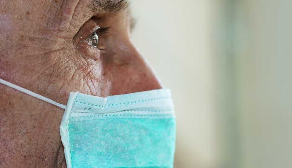 Perfil de un hombre mayor usando mascarilla con su mirada perdida