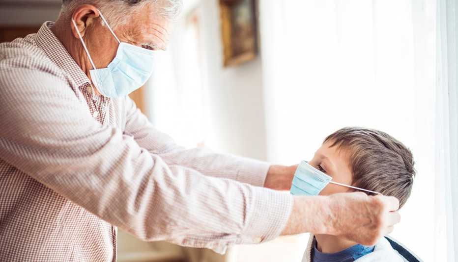 Un abuelo le pone una mascarilla a su nieto Un abuelo le pone una mascarilla a su nieto