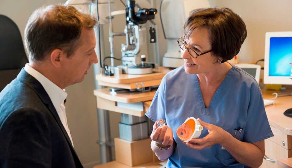 Una optómetra le muestra un modelo de un ojo a un paciente