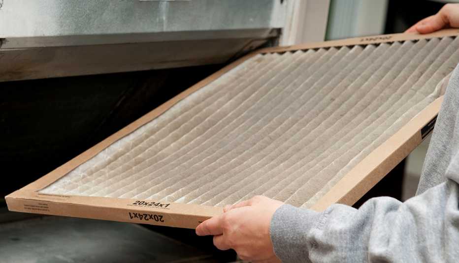 Una persona sostiene un filtro de un acondicionador de aire